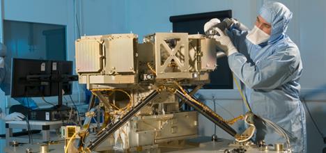 An engineer in a cleanroom suit performing alignment testing on MIRI.