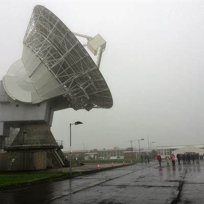 Visitors walk through the rain in front of the 25m dish