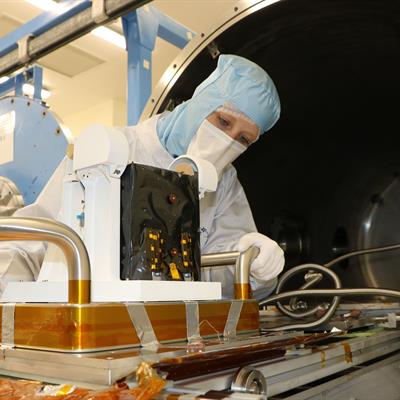 PITMS instrument being taken out of the thermal vacuum chamber by an engineer in a clean room suit.