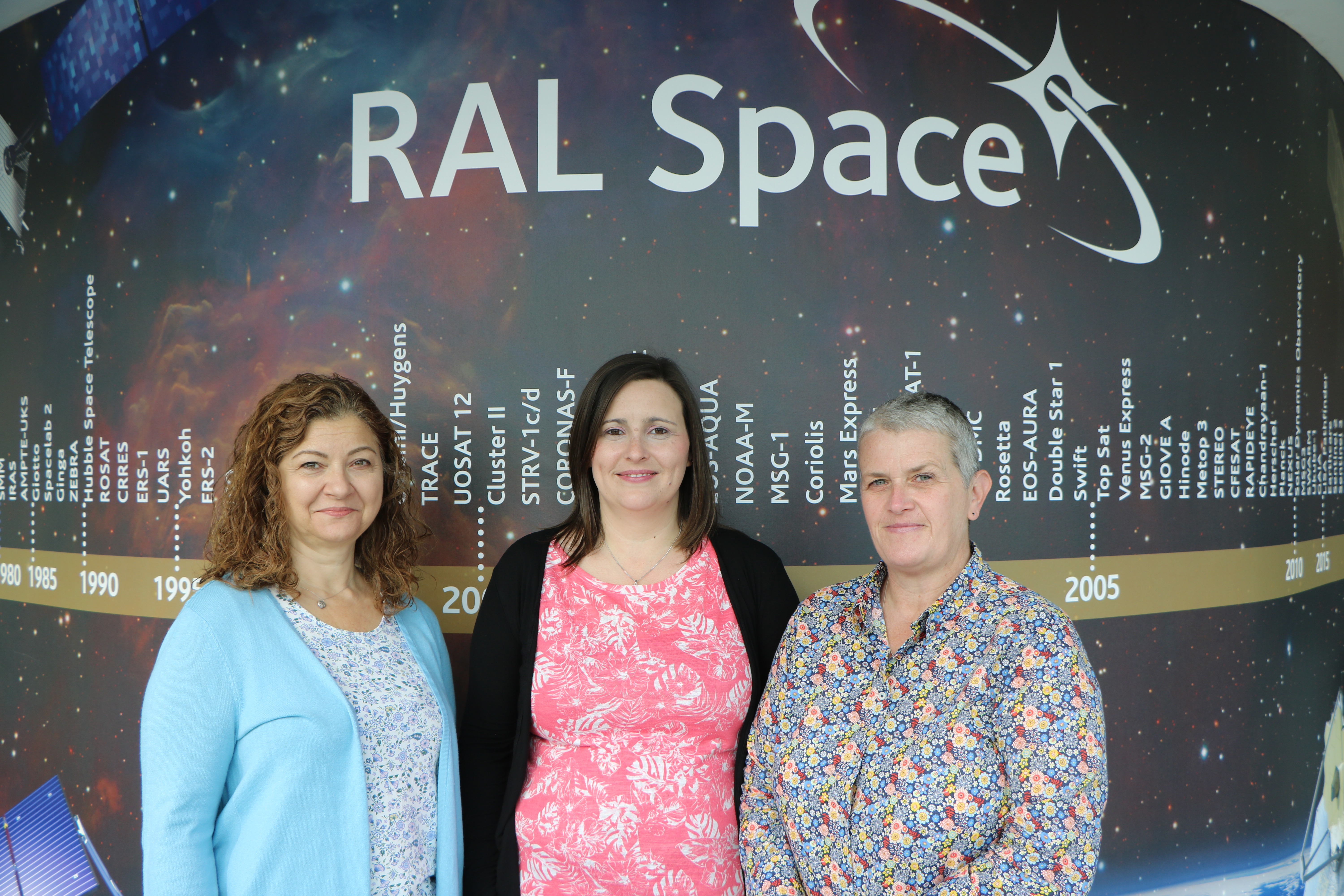 Claire, Kim and Anglea stand by the RAL Space missions timeline wall.
