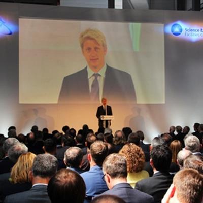 Jo Johnson speaking in front of an audience at the inauguration of R100.
