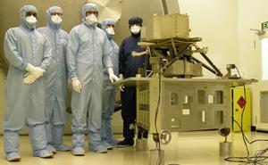 RAL Space engineers in cleanroom suits with the model of MIRI instrument.