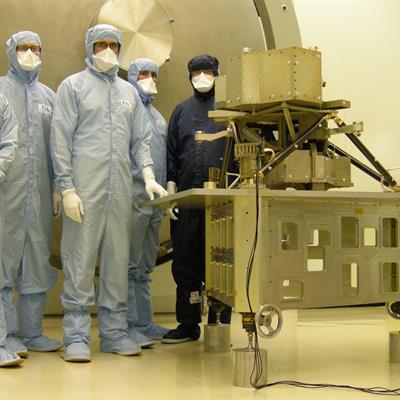 RAL Space engineers in cleanroom suits with the model of MIRI instrument.