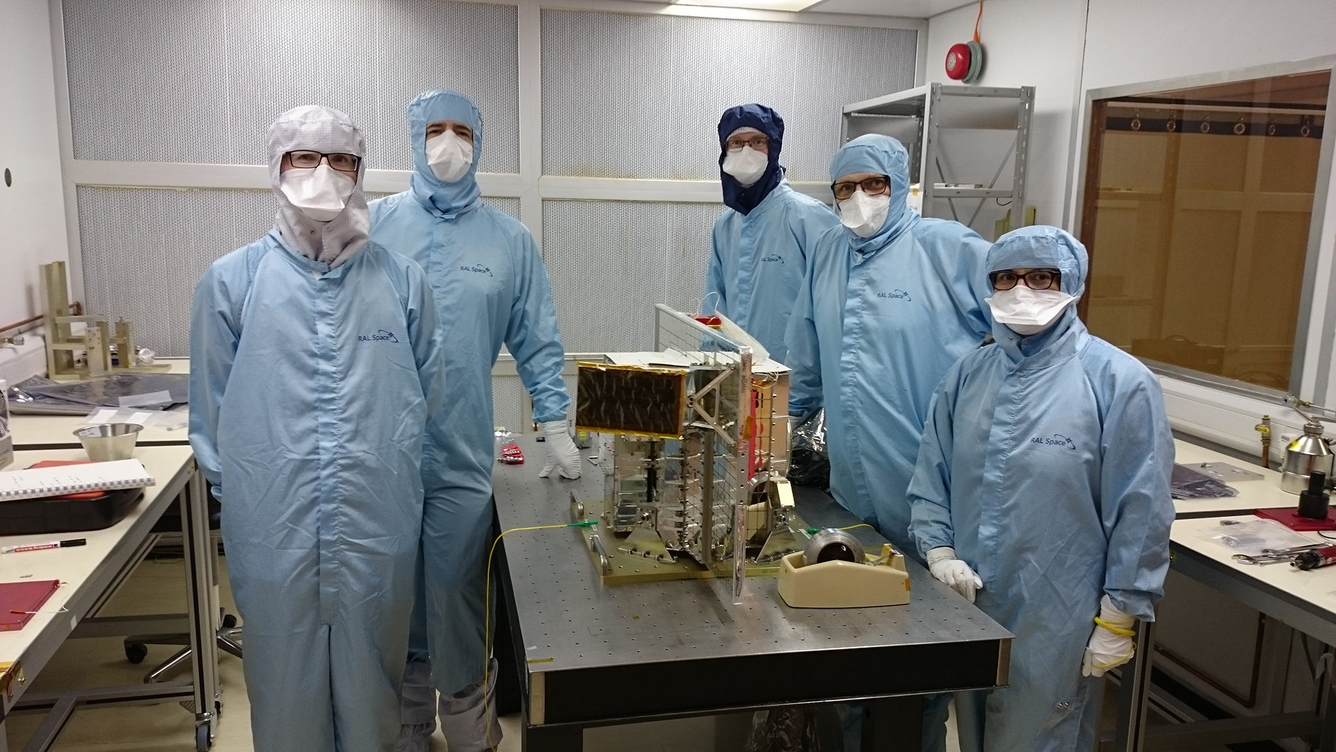 The project team stand next to BBR in a clean room.