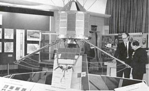 Black & white photo of two men looking at a model of Ariel 3.