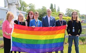 Group shot of the LGBTQ+ Group pictured at the Rutherford Appleton Laboratory. with the Pride rainbow flag.
