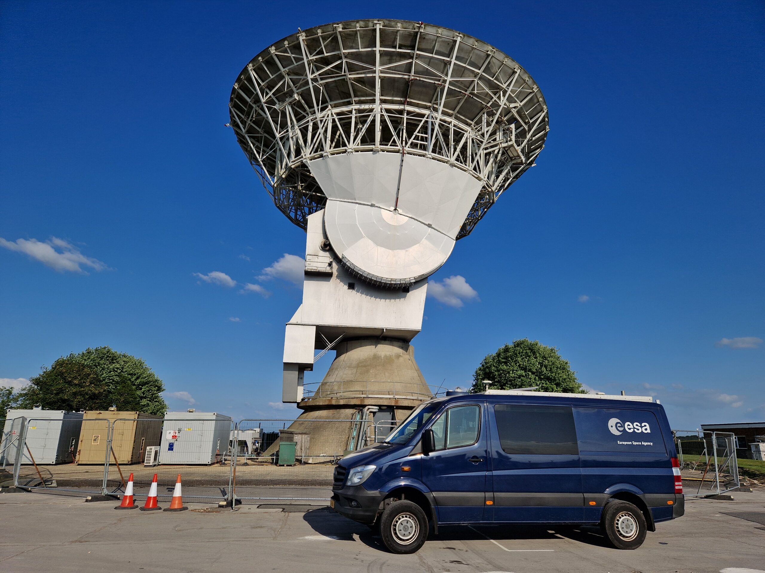 A dark blue ESA van stands at the ready in front of Chilbolton's 25-metre-wide antenna.