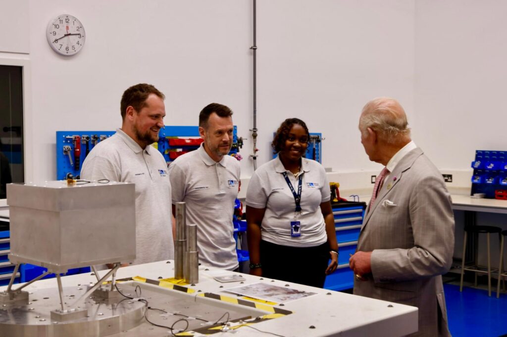 The King speaking to members of the dynamics test team in front of their small shaker table.