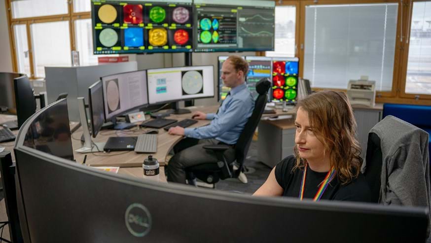 Met Office staff in a room with large screens showing various views and data on the Sun.