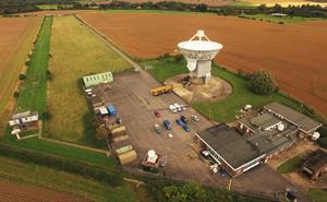 Aerial view of Chilbolton Observatory with buildings and a large white antenna.