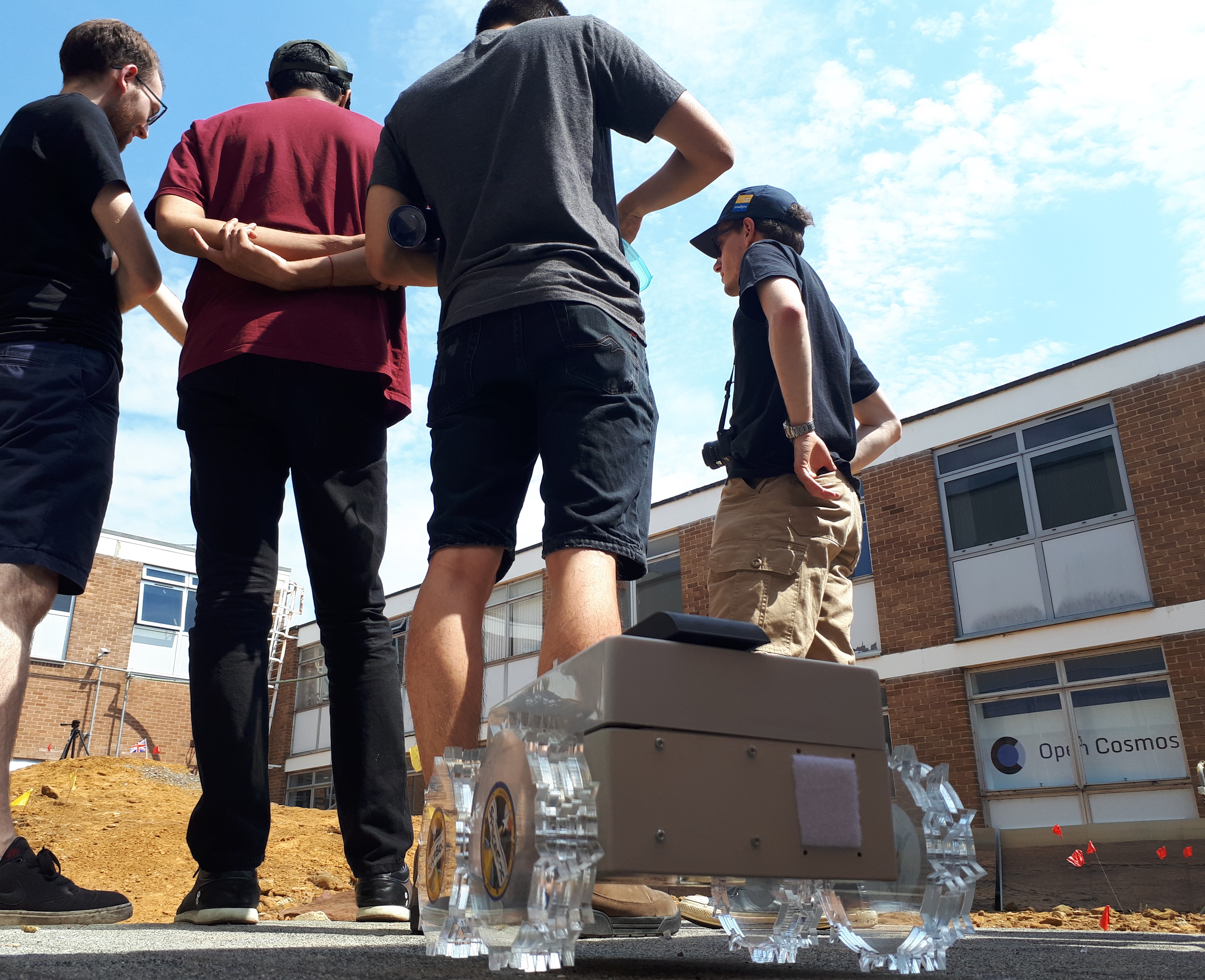 Students stand by their rover in the robotics trials area.