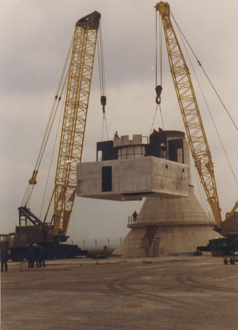 Two cranes placing antenna components in position.