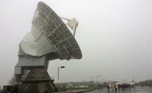 Visitors walk through the rain in front of the 25m dish